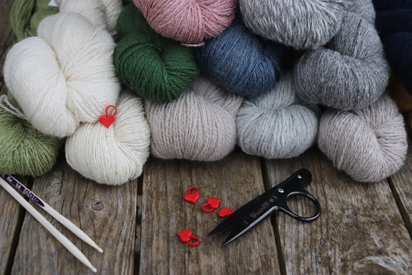 Image shows different yarns, some knitting needles, stitch markers and threadclips